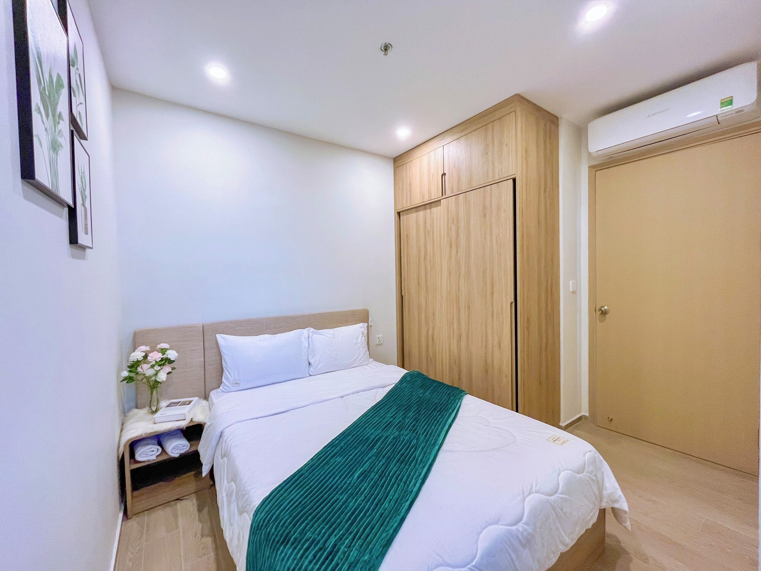 A neatly arranged hotel room with a bed, bedside table, and a wardrobe.