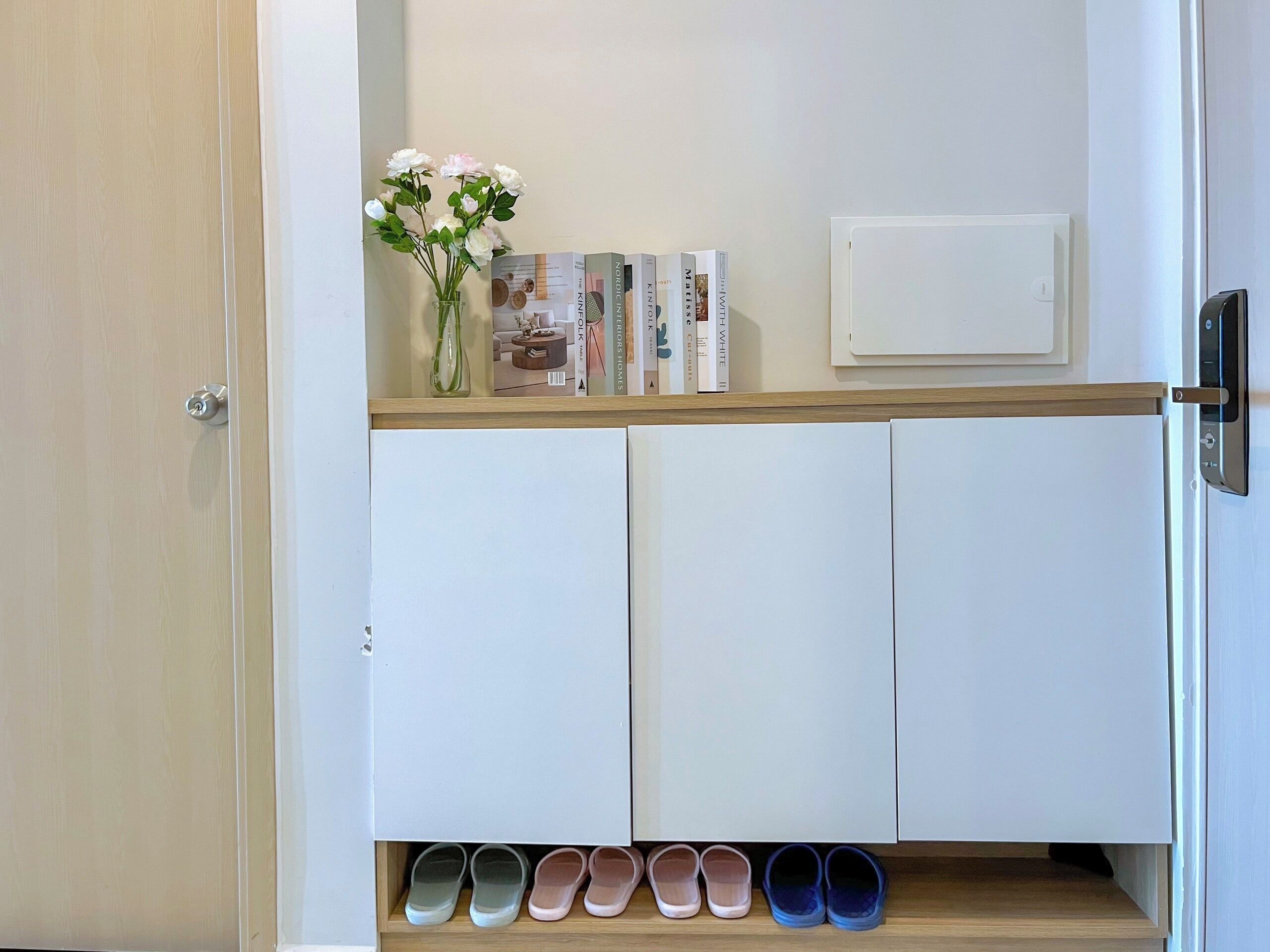 Een witte kast met een plank waarop boeken en een vaas met bloemen staan.