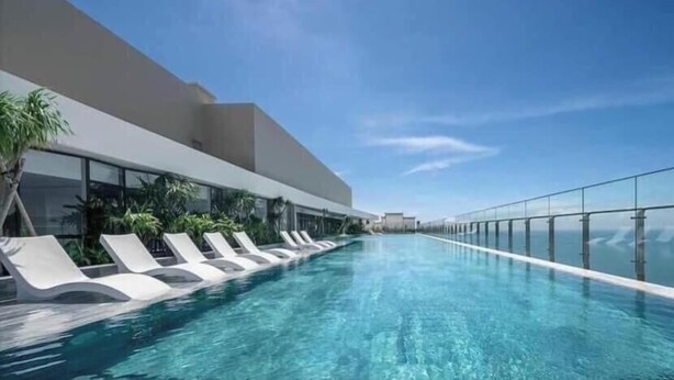 Een modern hotel met een dakterraszwembad, heldere luchten en een glazen reling.