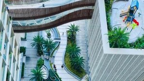 Een modern hotel met een zwembad op het dak, aangelegde terrassen en een opvallend, rond ontwerp.