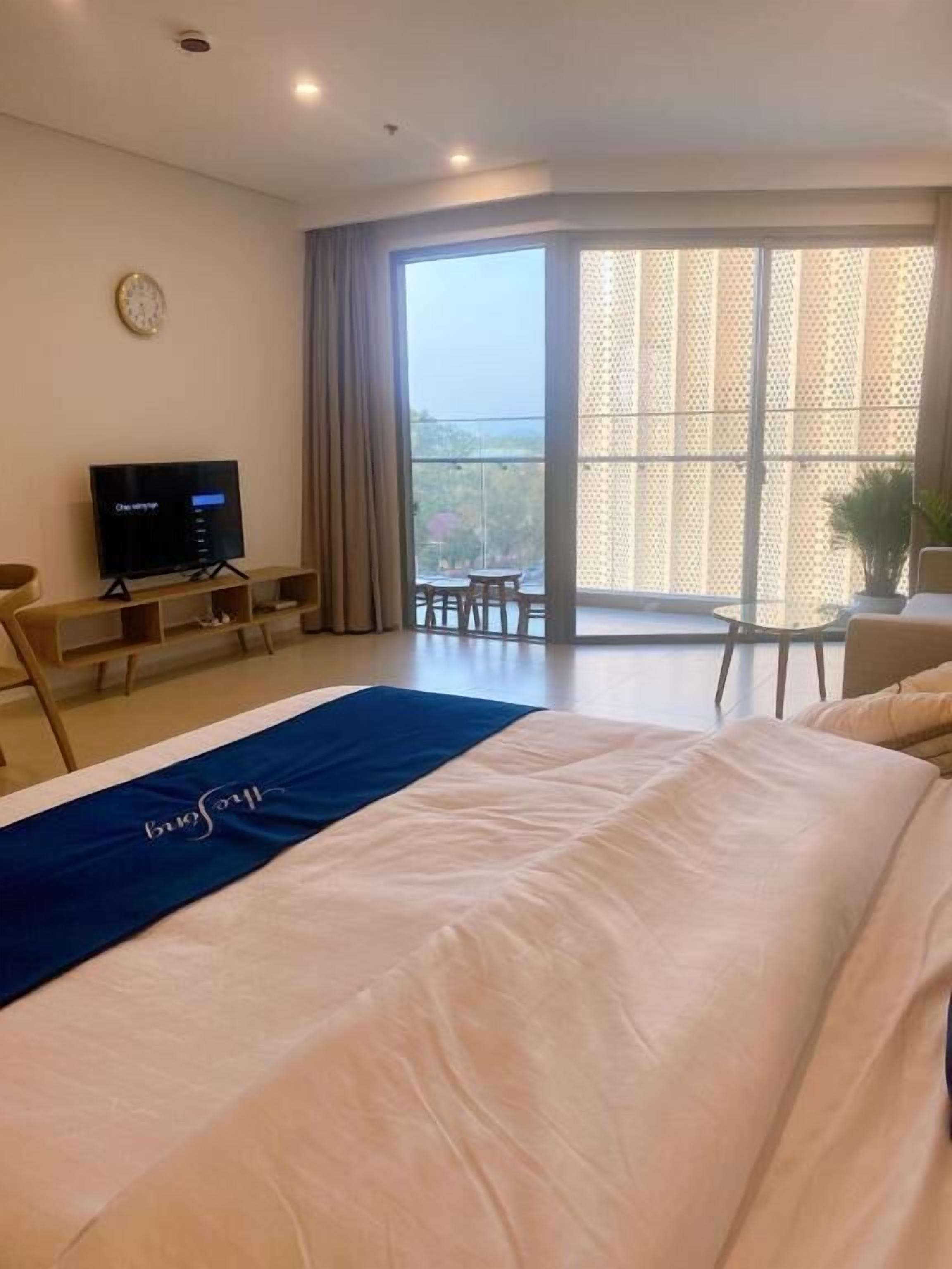 Ein Hotelzimmer mit Bett, Fernseher, Balkon mit Blick und Schreibtisch.