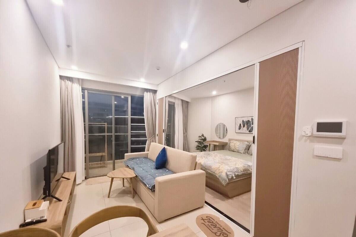 Una habitación de hotel moderna con un sofá, una mesita, un televisor, una cama y un espejo grande.