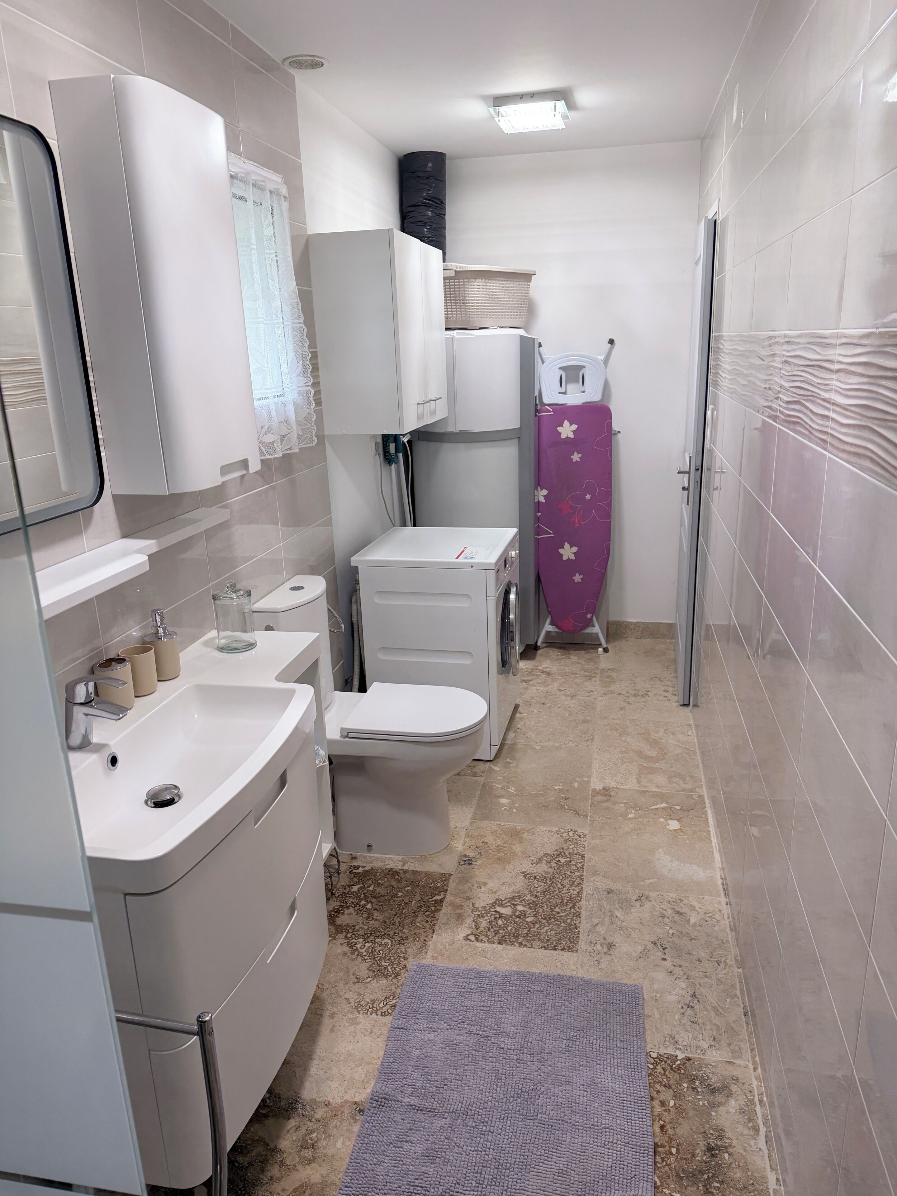 Een kleine badkamer met een wastafel, toilet en een wasmachine.