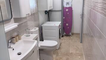 Een kleine badkamer met een wastafel, toilet en een wasmachine.
