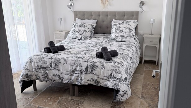 Ein Schlafzimmer mit einem Bett, zwei Nachttischen, einem Traumfänger und Blick ins Freie.