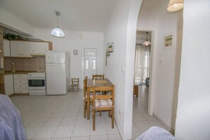 A compact kitchen with a dining area, a refrigerator, an oven, and a hanging light fixture.