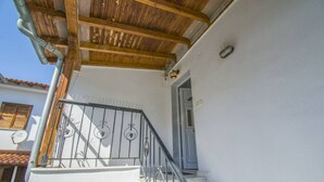 Ein weißes Gebäude mit einem Holzbalkon, einer Metalltreppe und einer Tür.