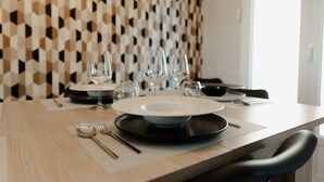 Une table à manger dressée avec des assiettes, des couverts et des verres à vin, avec un mur au motif géométrique en arrière-plan.