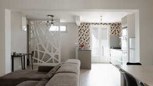 Une chambre moderne et minimaliste, comprenant un lit, une petite table et un coin cuisine.