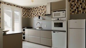Une cuisine moderne avec des meubles blancs, un four à micro-ondes, un four et un réfrigérateur.