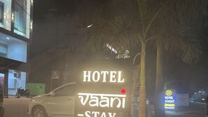 A sign for Hotel Vaani Stay with a contact number.