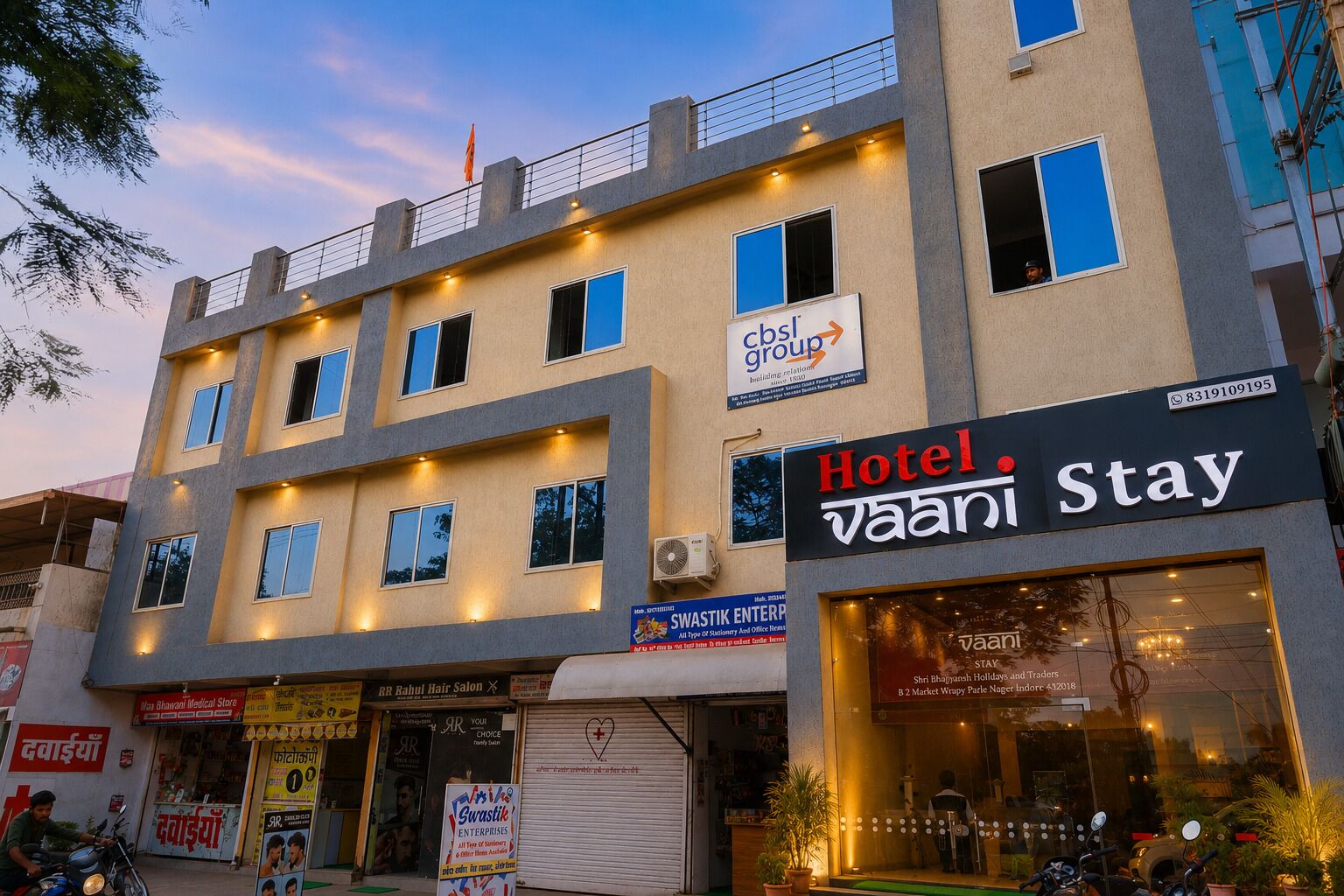 A multi-story building with a 'Hotel Stay' sign, a 'Swastik Enterprises' sign, and a 'RR Rahul Hair Salon' sign.