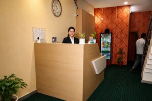 A reception desk with a clock, a menu board, and a refrigerator stocked with beverages. - Hotel Vaani Stay Bhopal (Bhopal)