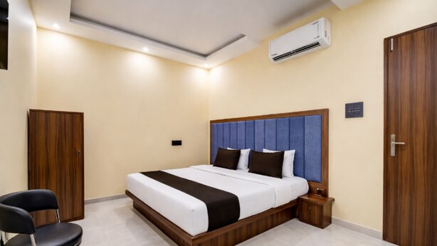 A bedroom with a bed, a chair, a wardrobe, and an air conditioning unit.