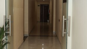 A corridor with glass doors, a potted plant, and a sign indicating room numbers.