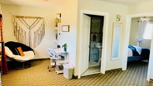 A living room with a patterned carpet, a sofa, a chair, a desk, and a bed in the adjacent room. - Awesome 1-bedroom apartment with AC in charming Page (Page)