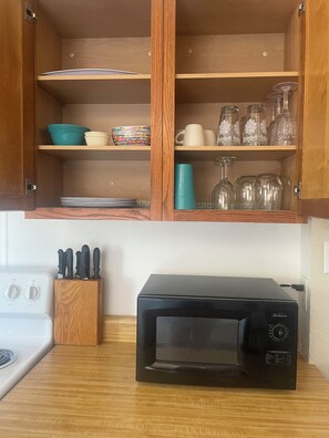 A kitchen with a microwave, wooden cabinets, and a knife block.