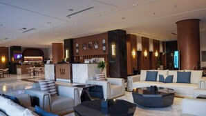 Un moderno vestíbulo de hotel con recepción, zona de estar y bar.