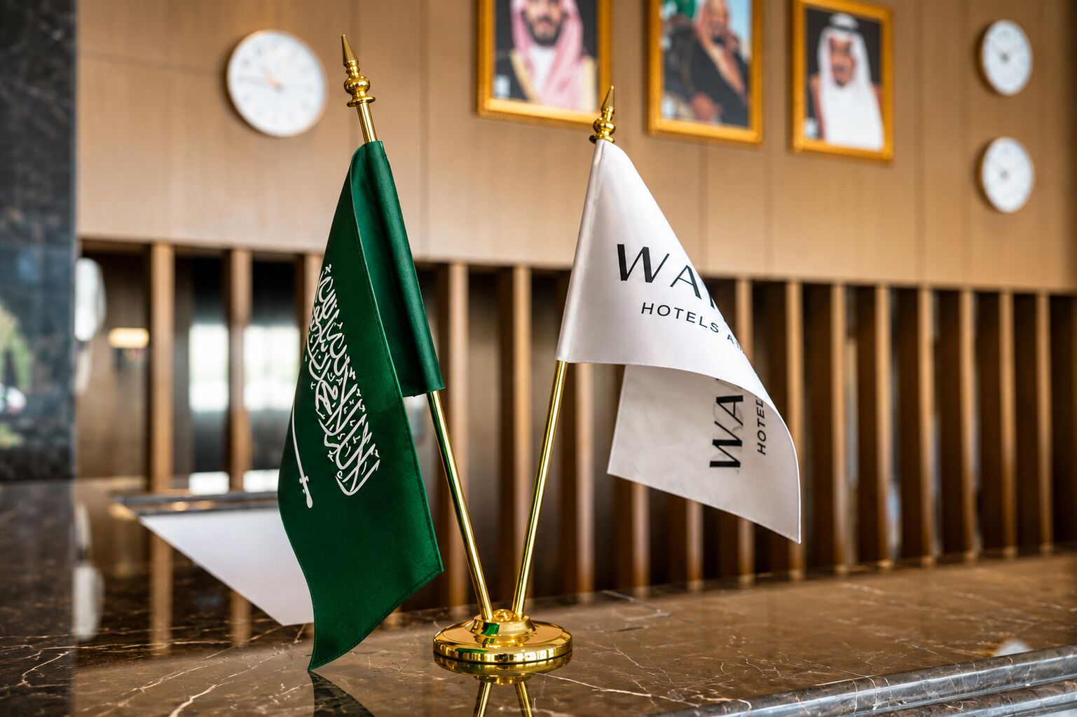Two flags on a marble surface with a clock and framed pictures in the background.