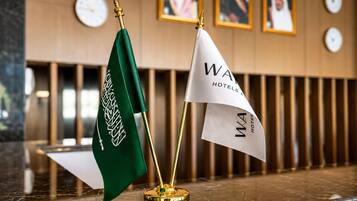 Two flags on a marble surface with a clock and framed pictures in the background.