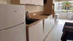 Uma cozinha moderna com frigorífico embutido, pia e janela com vista para palmeiras.