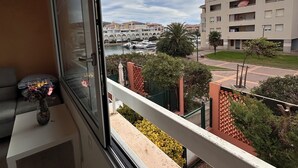 Uma varanda com vista para uma marina, um edifício com varandas e uma pequena mesa com um vaso.