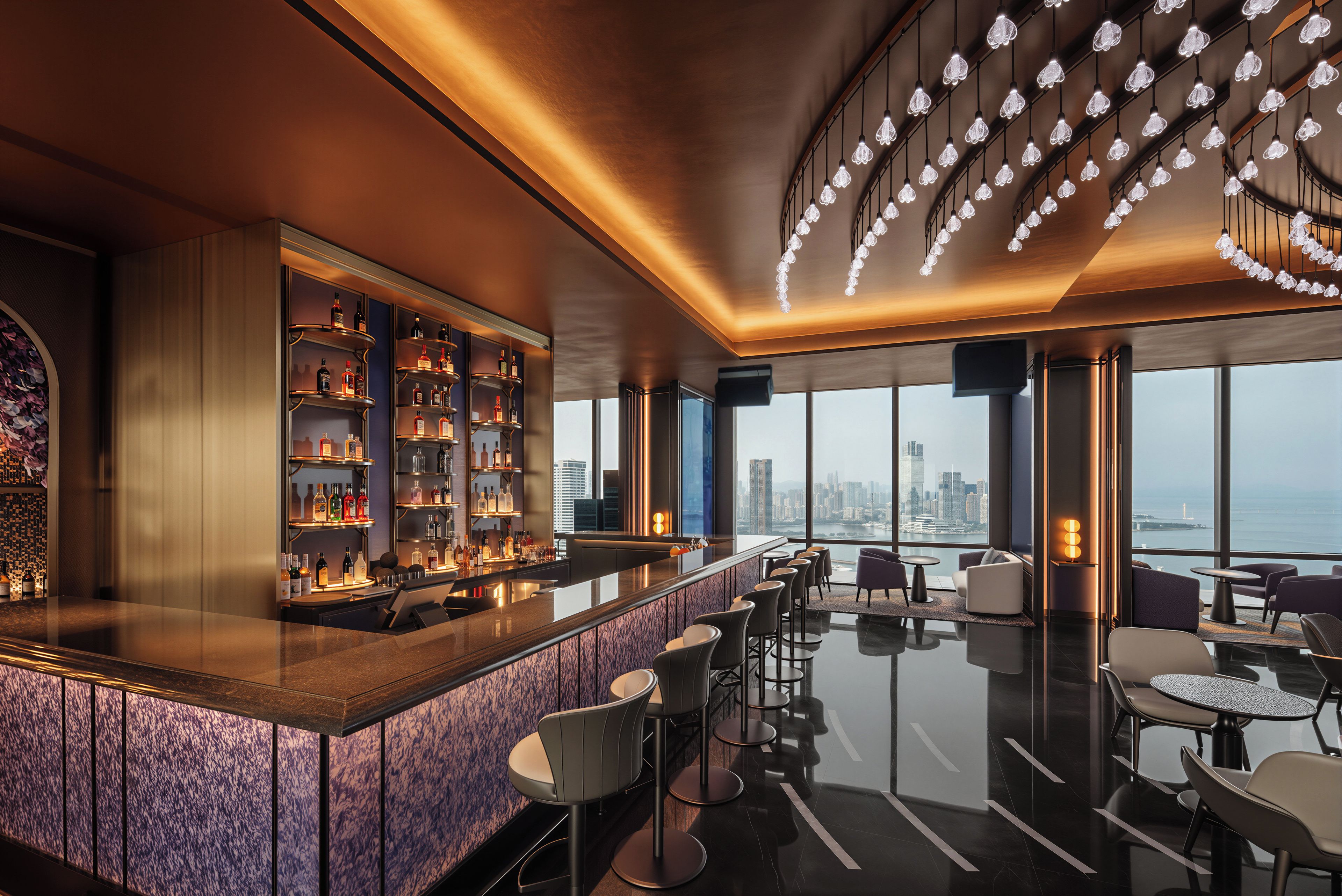 A modern bar area with a city view, bar stools, and a wine rack.