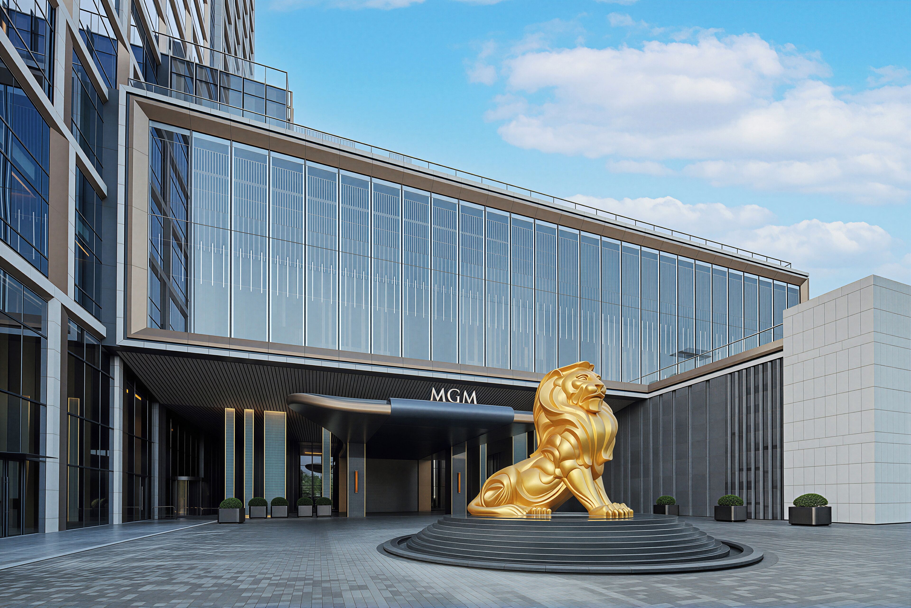 A modern building with a glass facade and a golden lion sculpture in front.