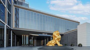 A modern building with a glass facade and a golden lion sculpture in front.