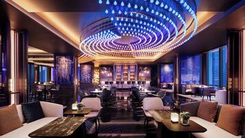 A modern interior with a central bar area, seating arrangements, and a distinctive ceiling light fixture.