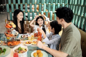A dining table with seafood dishes, a glass of orange juice, and a person wearing a white shirt. - MGM Shenzhen Prince Bay (Shenzhen)