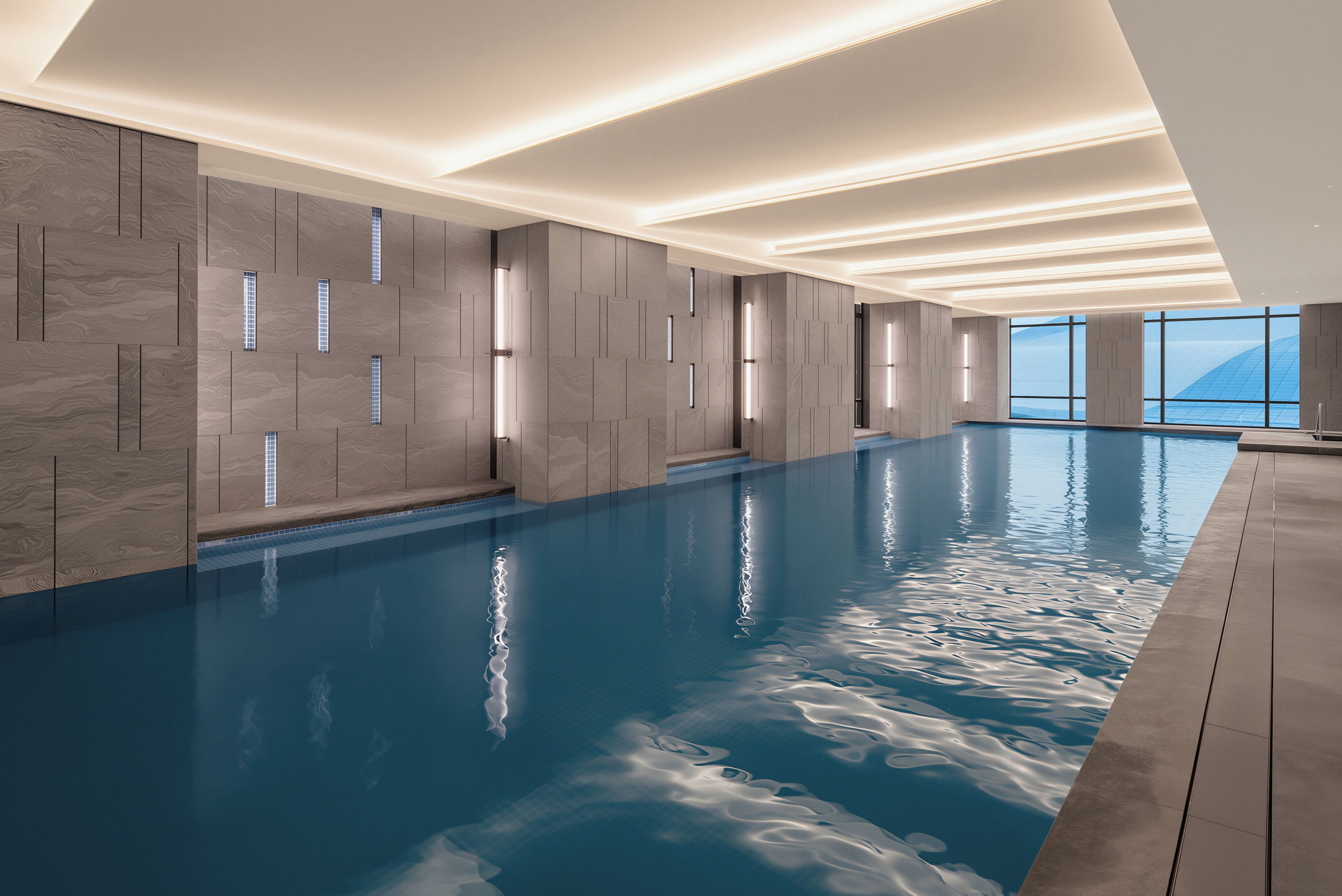 Une piscine intérieure moderne offrant une vue dégagée sur le ciel grâce à de grandes fenêtres.