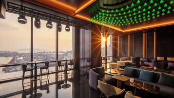 A modern interior with a bar area, seating, and a view of the cityscape.