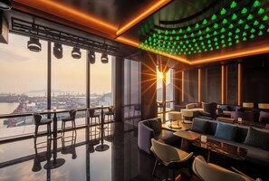 A modern interior with a bar area, seating, and a view of the cityscape. - MGM Shenzhen Prince Bay (Shenzhen)