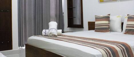 A bedroom with a bed, a ceiling fan, a window with curtains, a wall-mounted air conditioner, and a framed artwork.