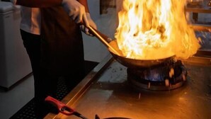 Un chef realiza una flambé con una sartén sobre una hornilla.