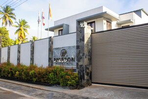 Un edificio moderno con fachada de piedra, entrada protegida por una reja y un cartel que indica 'BREEDON RESIDENCE HOTEL'.