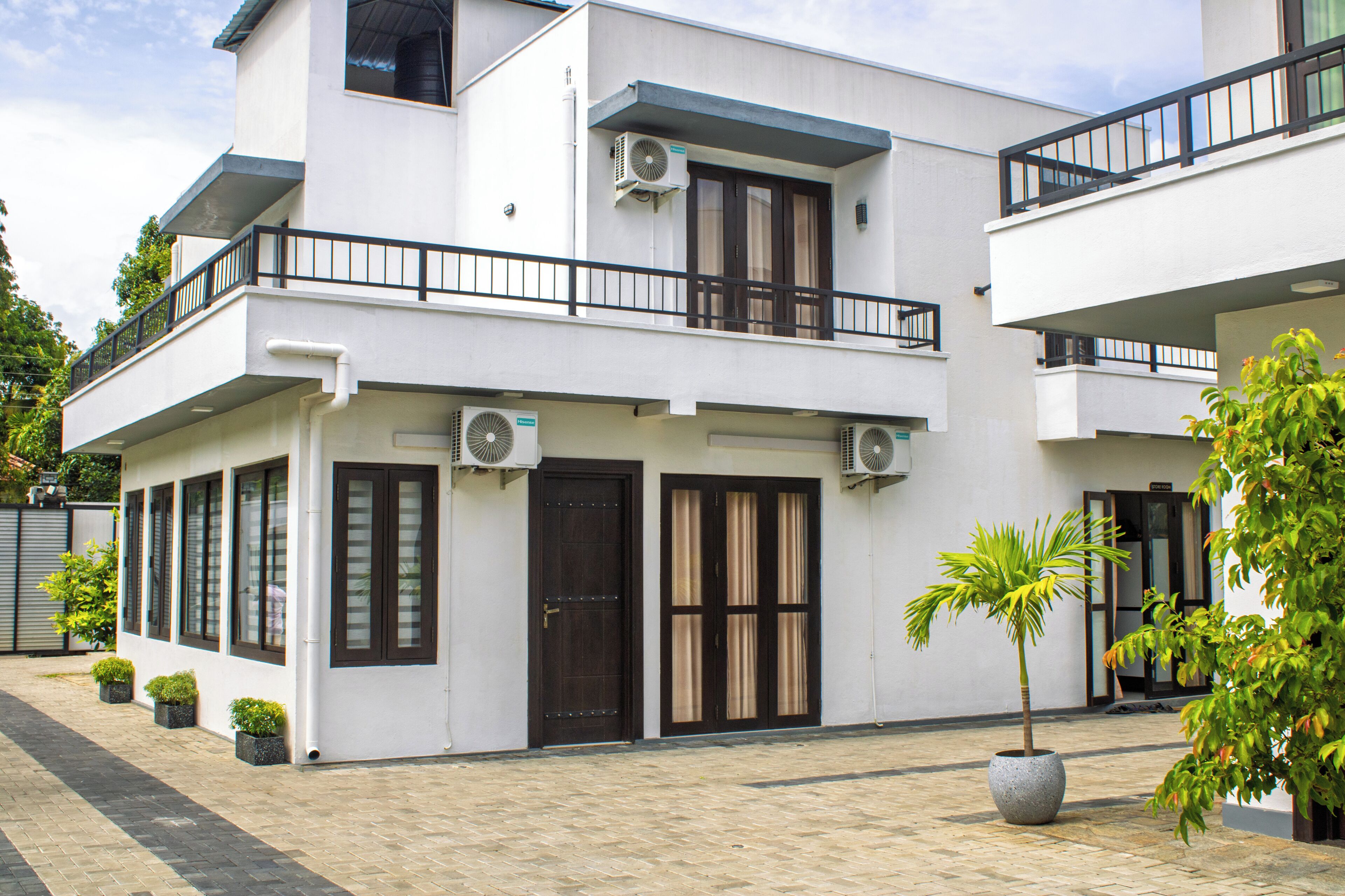 A modern two-story building with balconies, large windows, and air conditioning units.