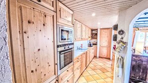 A kitchen with wooden cabinets, a built-in oven, and a tiled floor. - Chalet Le Rhônasson by Interhome (Vercorin)