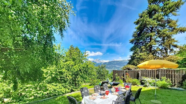 A dining table set outdoors with chairs, a yellow umbrella, and a view of mountains in the background. - Chalet Le Rhônasson by Interhome (Vercorin)