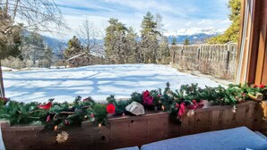 A room with a large window overlooking a snowy landscape, a wooden bench, and a Christmas tree with decorations. - Chalet Le Rhônasson by Interhome (Vercorin)
