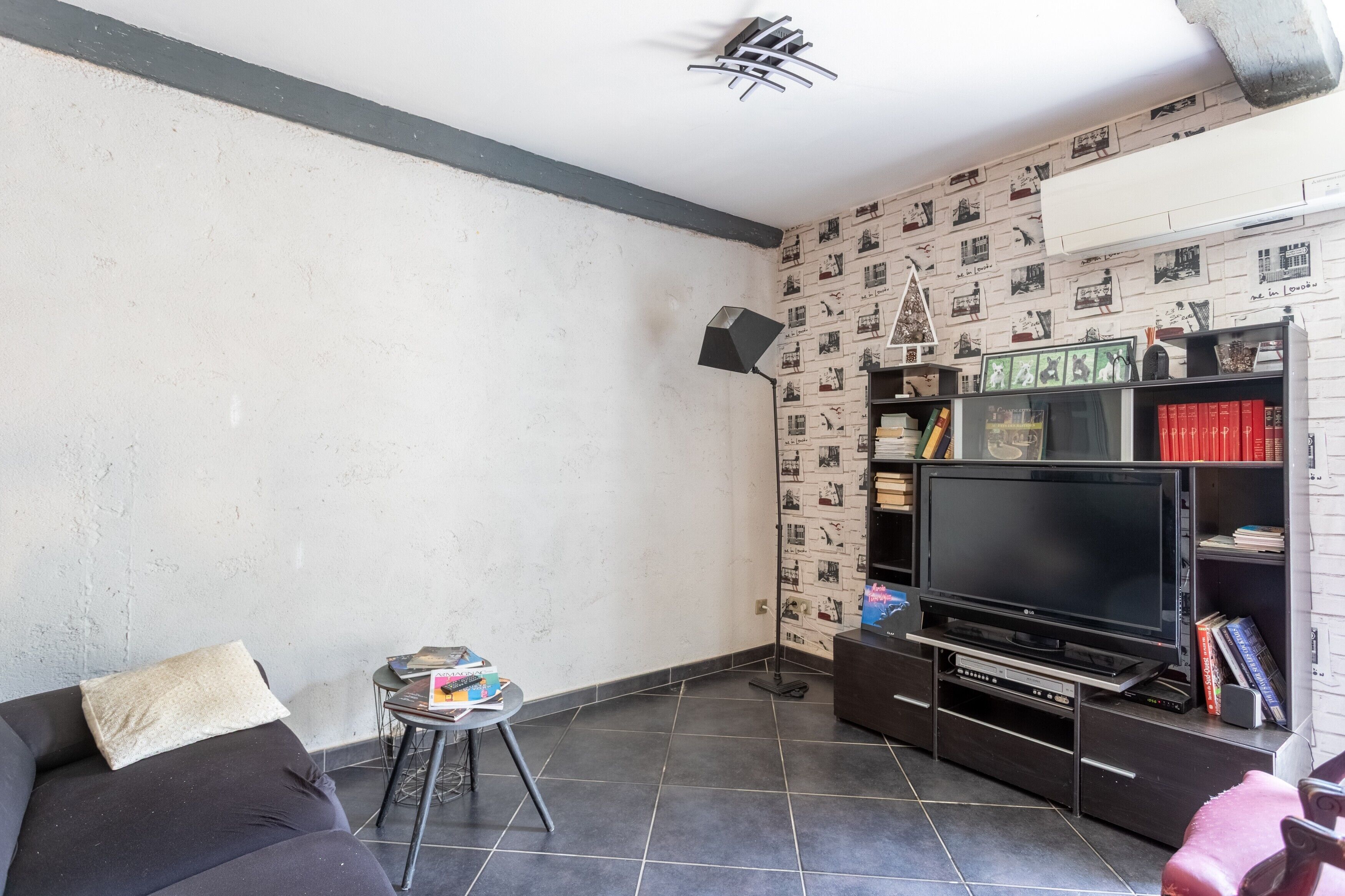 A living room with a sofa, a small table, a TV, and a bookshelf.
