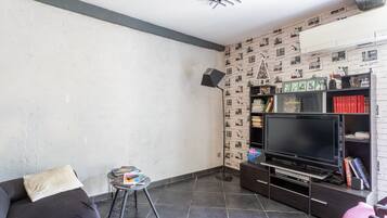 A living room with a sofa, a small table, a TV, and a bookshelf.