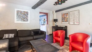 A living room with a sofa, two red chairs, a coffee table, and artwork on the walls.