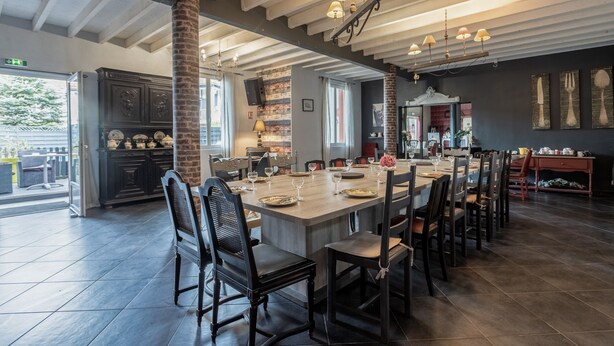 A spacious dining area with a long table, chairs, and hanging pendant lights.