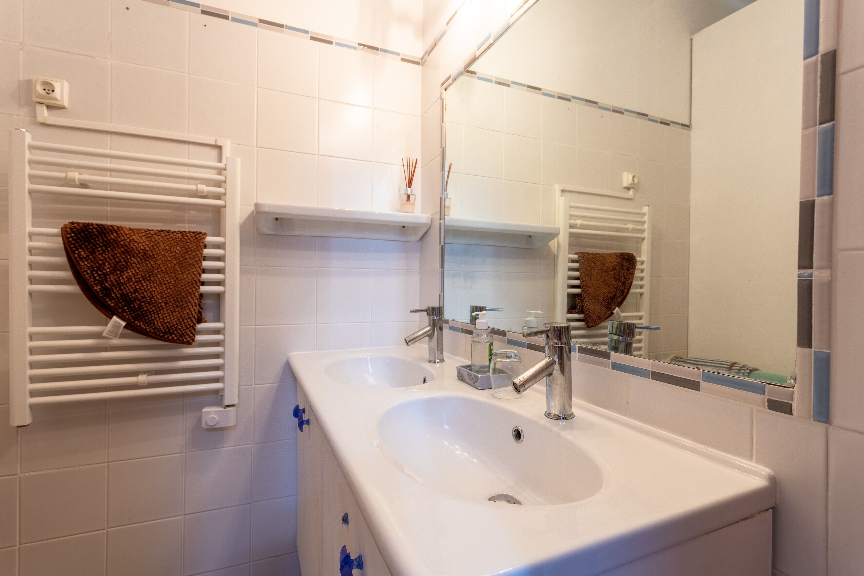 Een badkamer met twee wastafels, een spiegel en handdoekrekken.
