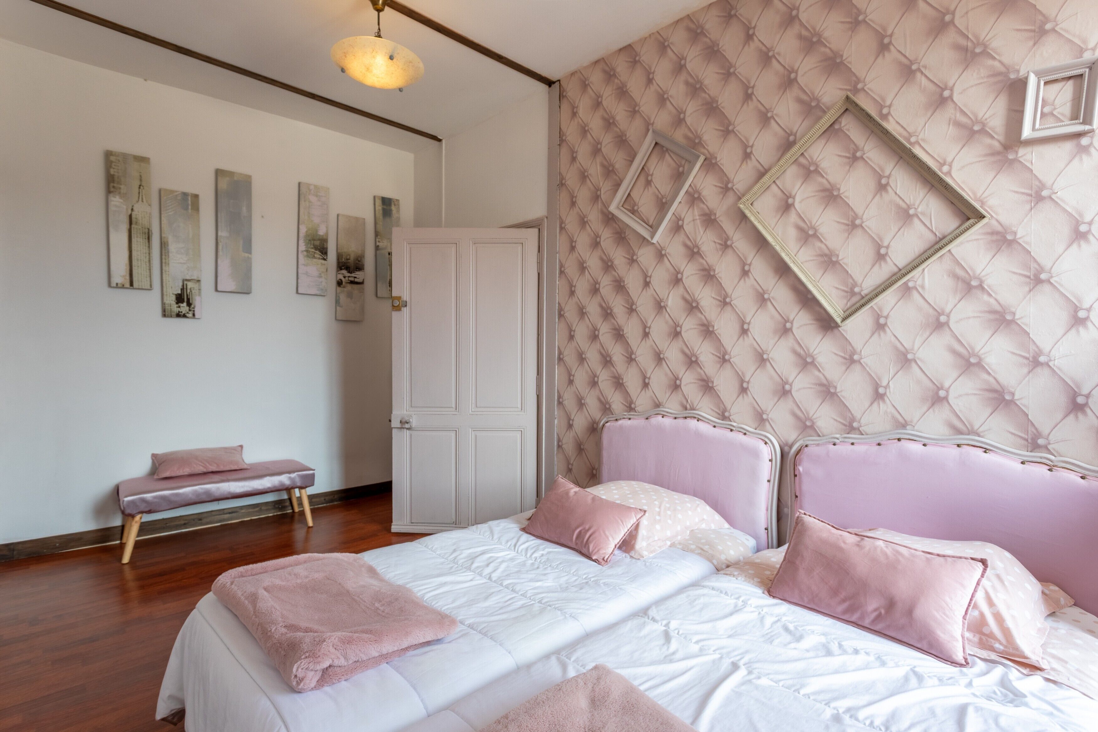 A bedroom with a bed, a bench, a door, and wall decorations.