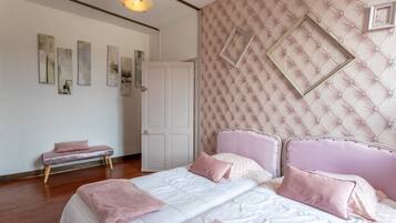 A bedroom with a bed, a bench, a door, and wall decorations.