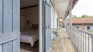 A balcony with a bed, a table, and chairs.