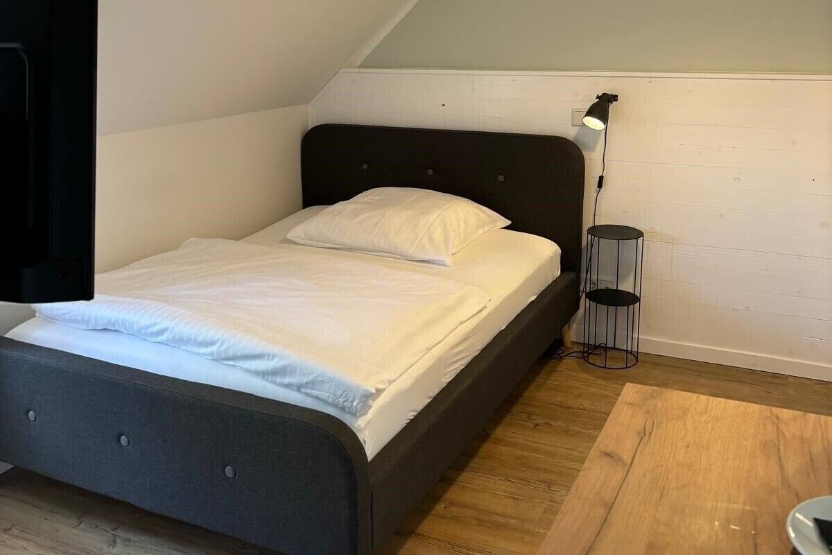 Ein Schlafzimmer mit einem Bett, einem Schreibtisch, einer Lampe und einer Deckenleuchte.